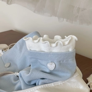 Détail de chaussettes bleu clair avec bords à volants blancs et pendentif cœur perlé