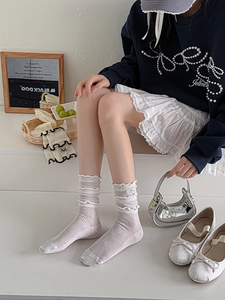 Detail of cream slouch socks with delicate lace edges and ribbed cotton knit texture