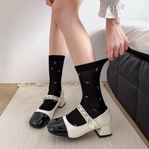 Détail de chaussettes à fleurs vintage portées avec des Mary Janes bicolores à perles