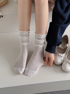 Close-up of beige ribbed mid-tube socks featuring delicate triple-layered lace trim