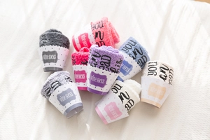Flat lay of colorful coral fleece wine socks in polka dot cupcake gift packaging
