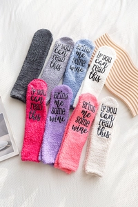 Macro shot of fluffy coral fleece socks with funny letter print on soles in multiple colors