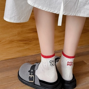 Detail of white cotton socks with cute puppy embroidery and red contrast cuffs