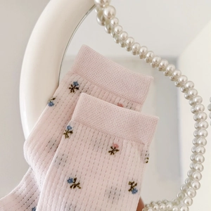 Gros plan de chaussettes en résille rose clair avec broderie florale et bords