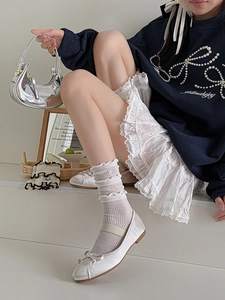 Detailed view of layered off-white lace trim socks paired with silver Mary Jane shoes