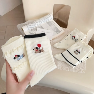 Detail of cream crew socks with cartoon dog embroidery and elegant wavy ruffle edge