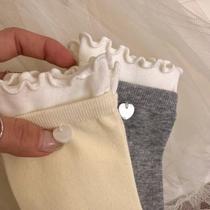 Détails des bords à volants et boutons cœur sur chaussettes en maille beige et gris