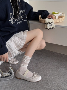 Detail showing cream-white ribbed socks with ruffle trim and bow embroidery for a balletcore style