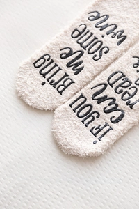 Macro shot of fluffy coral fleece socks with If you can read this bring me wine text