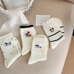 Close-up of four white mesh knit socks with cute dog embroidery and ruffled cuffs