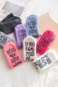 Close-up of fluffy coral fleece socks with non-slip letter printing on soles