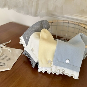 Détail de chaussettes pastel avec bordures à volants blancs et boutons perle cœur