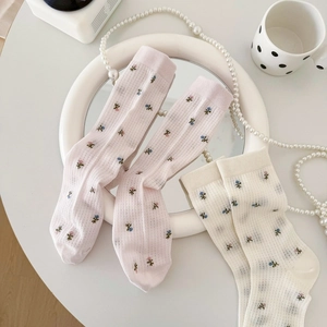 Détail de motifs floraux et texture mesh sur chaussettes rose pastel et beige