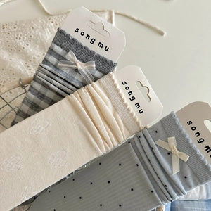 Detailed view of light blue and grey bow socks with embroidery in a woven basket