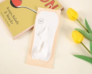 Atmungsaktive weiße Mesh-Füßlinge mit Original-Papierverpackung auf gemütlichem Hintergrund