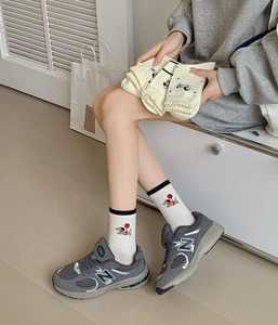 Close-up of white cotton socks with cute dachshund embroidery and black ribbed cuffs
