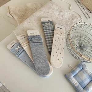 Flat lay of five pairs of assorted grey and blue cotton socks with bow and floral patterns