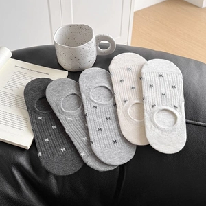 Detalle de calcetines invisibles de malla con lazo en tonos gris y beige