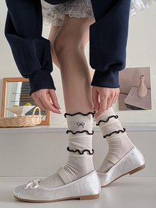 Close-up of beige knitted socks with brown ruffled edges and bow embroidery detail