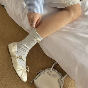 Detail of light blue polka dot socks with lace trim paired with beige satin bow flats