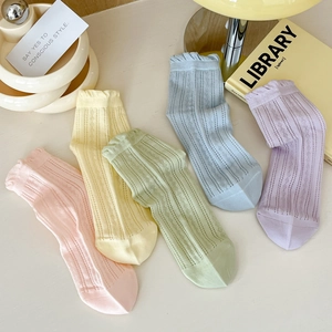 Vue à plat de chaussettes en résille aux couleurs macaron avec bords festonnés