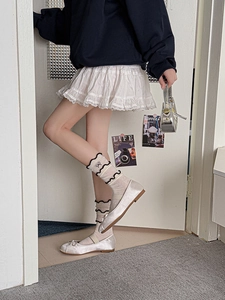 Close-up of white ruffled crew socks paired with silver satin ballet flats and cake skirt