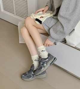 Detail of white cotton socks with cute cartoon dog embroidery and ruffled lettuce edges
