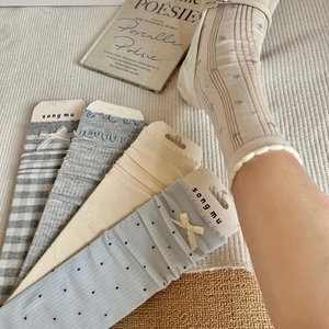 Close-up of Japanese style gray-blue socks with bow details and ribbed cotton texture
