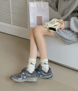 Close-up of white ruffled ankle socks featuring a cute embroidered puppy dog design