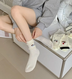 Detail of white cotton sock with ruffle trim and cute colorful puppy embroidery