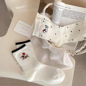 Close-up of cream cotton socks with dog embroidery and vintage prop background