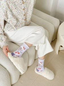 Close-up of lavender fuzzy socks with cute patterns and plush slippers for home warmth