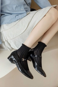 Détail de chaussures Mary Jane en cuir verni noir avec chaussettes résille