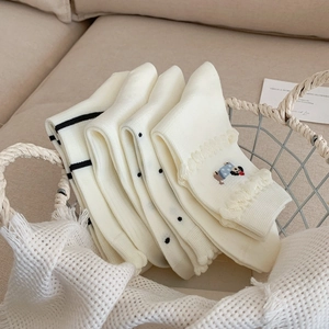 Detailed view of white cotton socks with lace trim and bear embroidery in a metal basket