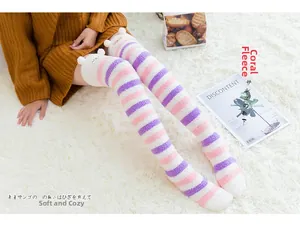Détail de chaussettes hautes rayées en molleton corail avec pompons blancs pour l'hiver