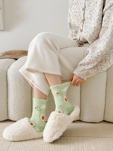 Close-up of soft green coral fleece socks with red polka dots for winter warmth