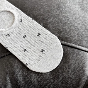 Primer plano de calcetines invisibles grises con jacquard de monograma y tejido de malla