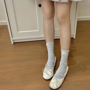 Detail of light blue crew socks featuring black polka dots and a white bow decoration
