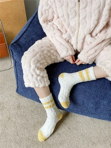 Detail of white and yellow coral fleece socks with striped pattern on blue chair