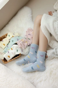 Detail of warm thick coral fleece socks with heart embroidery in a cozy basket