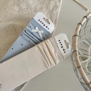 Detailed view of light blue polka dot socks with bow and cream jacquard cotton socks