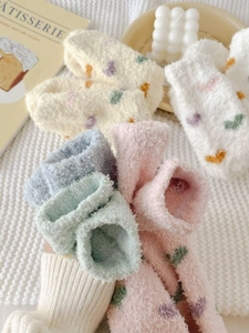 Close-up of soft coral fleece heart socks on a cozy white knit blanket background
