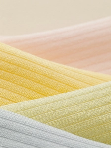 Macro detail of ribbed knit modal socks in soft pink, yellow, beige and light blue