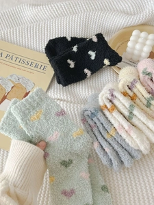 Detailed view of heart pattern coral fleece socks in various colors on cozy background