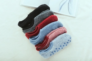 Detail view of anti-slip silicone grippers on warm coral fleece floor socks displayed on rug