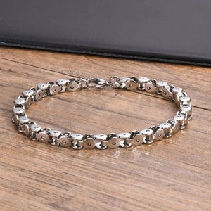 Close-up of a silver stainless steel bicycle chain bracelet on a black leather tray