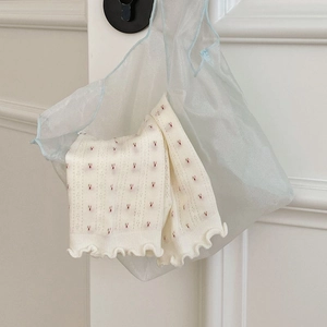 Detail von cremefarbenen Socken mit Blumenmuster und Rüschenrand in Netztasche