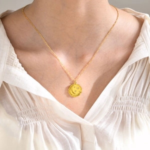 Détail du collier doré avec pendentif étoile et lune porté sur une chemise blanche texturée