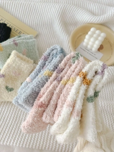 Close-up of thick coral fleece socks in soft pastel colors on a cozy knit blanket