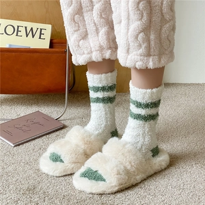Close-up of thick coral fleece striped socks and white plush slippers for home
